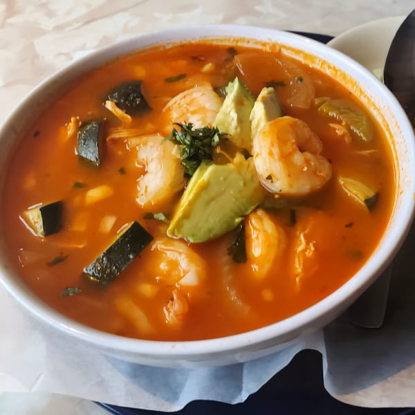 Kico's Méxican Food's shrimp soup with avocado, zucchini, and cilantro in a white bowl.