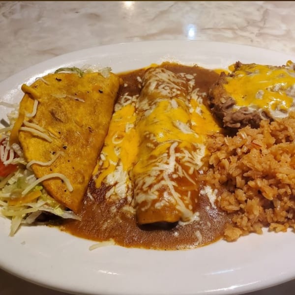 A Kico's Mexican Food combo plate with a taco, two enchiladas, refried beans, and rice.