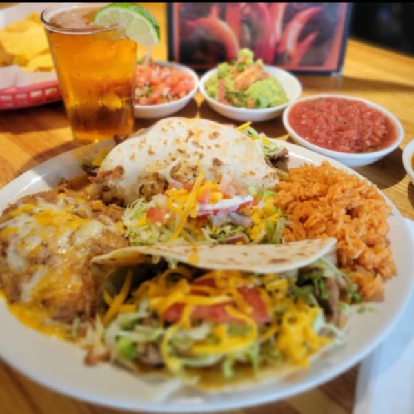 A Kico's Mexican Food combo plate with tacos, rice, beans, and a beer with lime.
