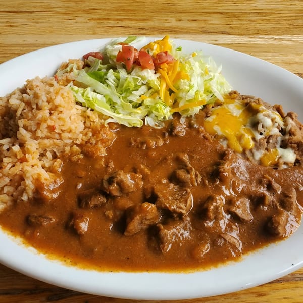 Kico's Mexican food plate with stewed beef, rice, refried beans with cheese, and a side salad.