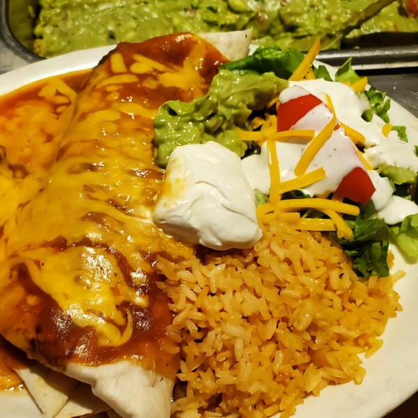 Kico's Mexican Food enchiladas with rice, guacamole, sour cream, and a side salad.